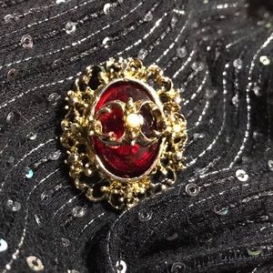 Gold brooch with red stone.
